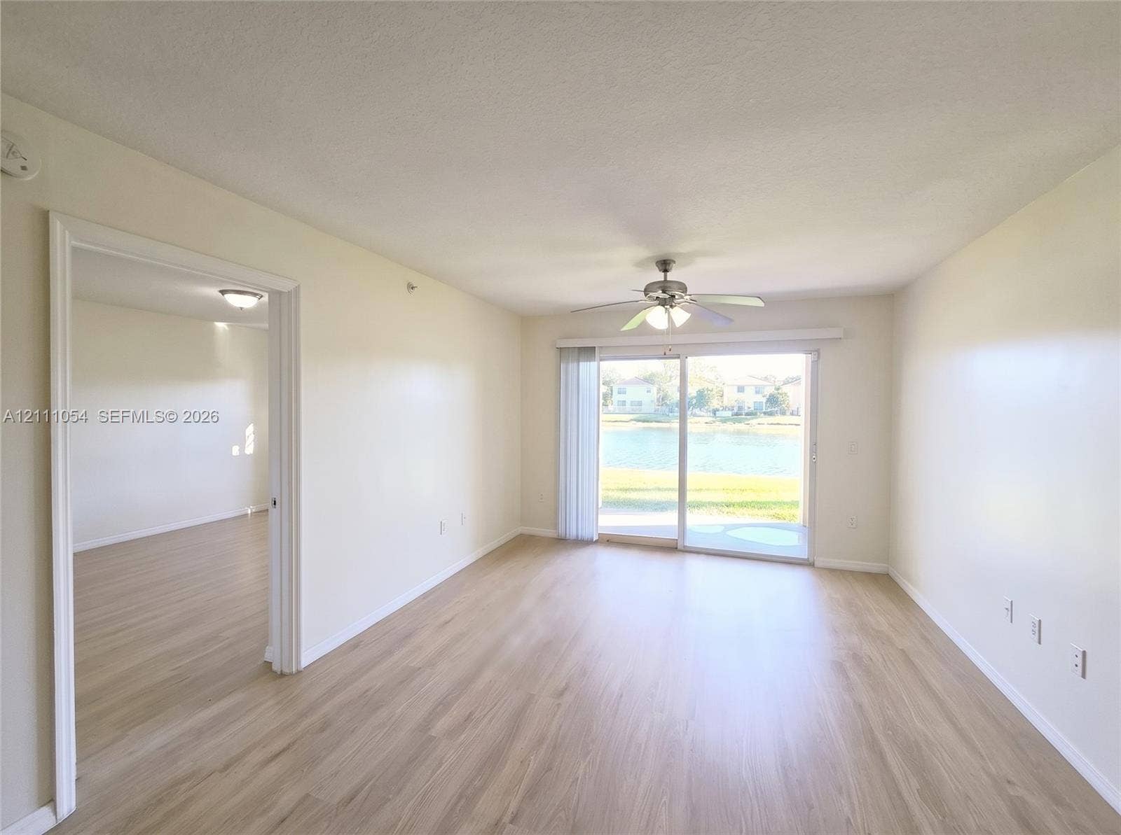 4180 San Marino Boulevard, #106, West Palm Beach, FL 33409 Living area featuring wood-finish flooring, sliding glass door, ceiling fan with integrated lighting, and neutral wall tones