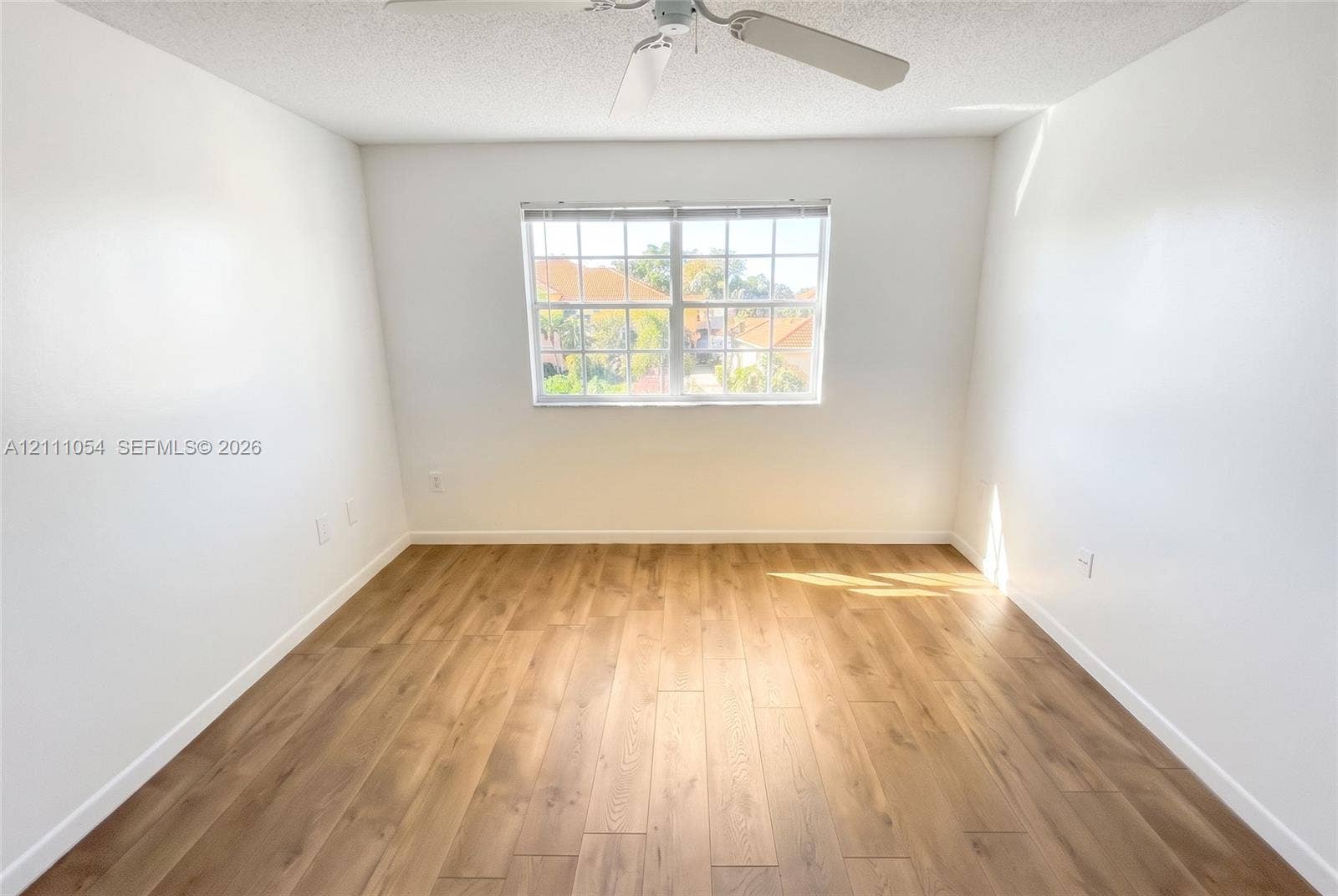 4180 San Marino Boulevard, #106, West Palm Beach, FL 33409 Room featuring wood-finish flooring, a multi-pane window, and a ceiling-mounted fan