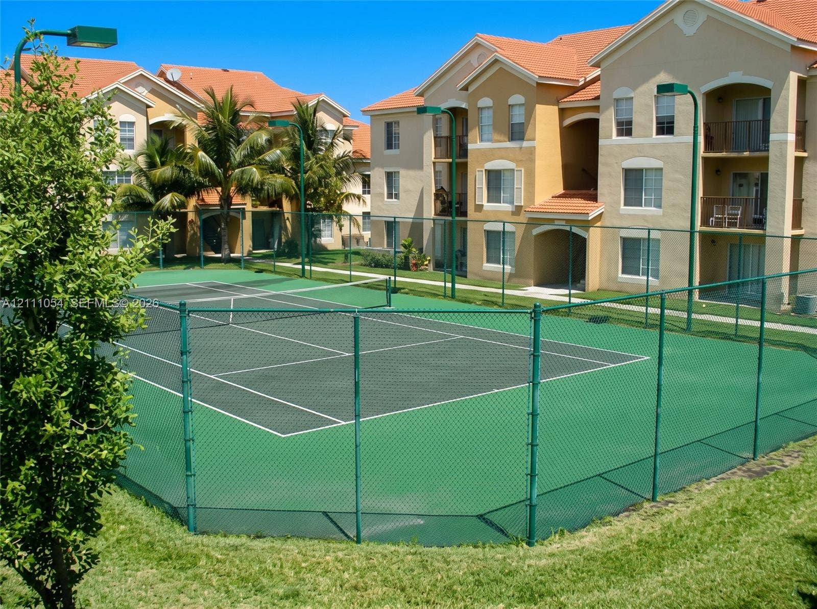 4180 San Marino Boulevard, #106, West Palm Beach, FL 33409 Tennis court with perimeter chain-link fencing, painted surface, and integrated net