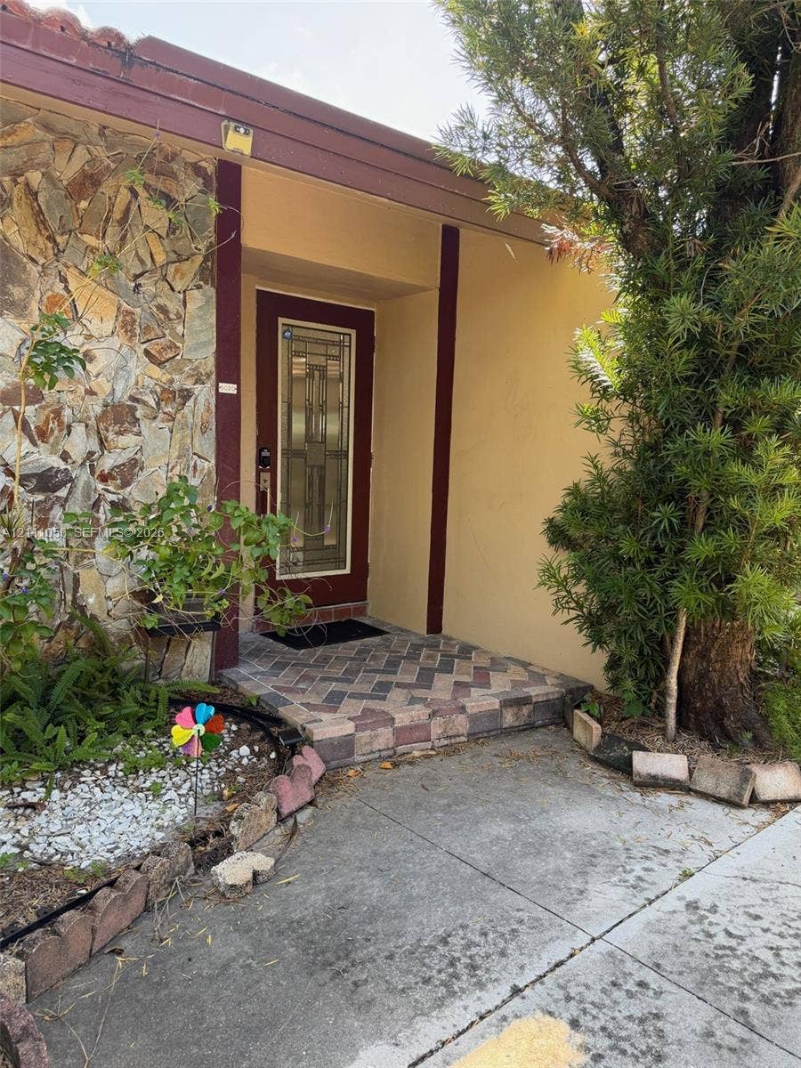 5020 Sheridan Street, #2, Hollywood, FL 33021 Entryway featuring a stone-veneer exterior facade, herringbone-patterned brick paver landing, and a decorative glass-panel front door