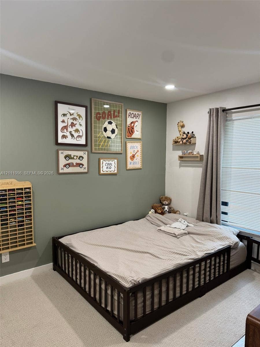 5020 Sheridan Street, #2, Hollywood, FL 33021 Neutral-toned interior space featuring a sage green accent wall, wall-to-wall carpeting, recessed ceiling lighting, and window with attached curtain rod and blinds