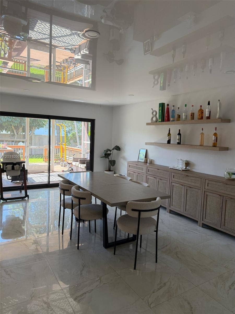 5020 Sheridan Street, #2, Hollywood, FL 33021 Glossy tile flooring, built-in wooden cabinetry with shaker-style doors, dual floating wood shelves, and large sliding glass doors