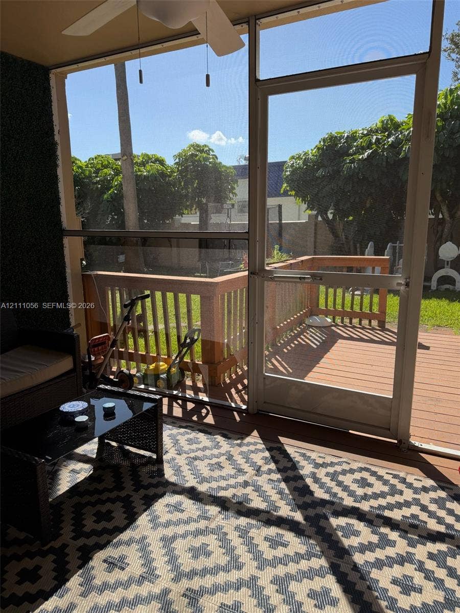 5020 Sheridan Street, #2, Hollywood, FL 33021 Screened-in porch featuring a ceiling fan, wood-toned deck, metal railings, and a direct-entry screen door