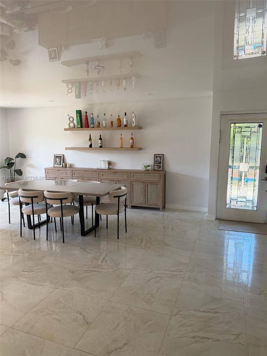 5020 Sheridan Street, #2, Hollywood, FL 33021 Large-format tiled flooring throughout, built-in wooden cabinetry with textured door fronts, dual wall-mounted floating wood shelves, and a front entry door featuring decorative geometric glass panes