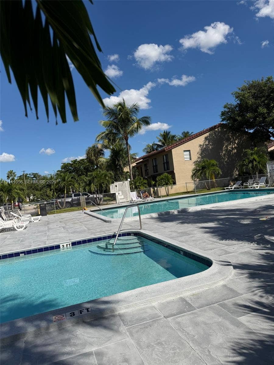 5020 Sheridan Street, #2, Hollywood, FL 33021 In-ground swimming pool with built-in stairs, metal handrail, and stone-tiled pool deck