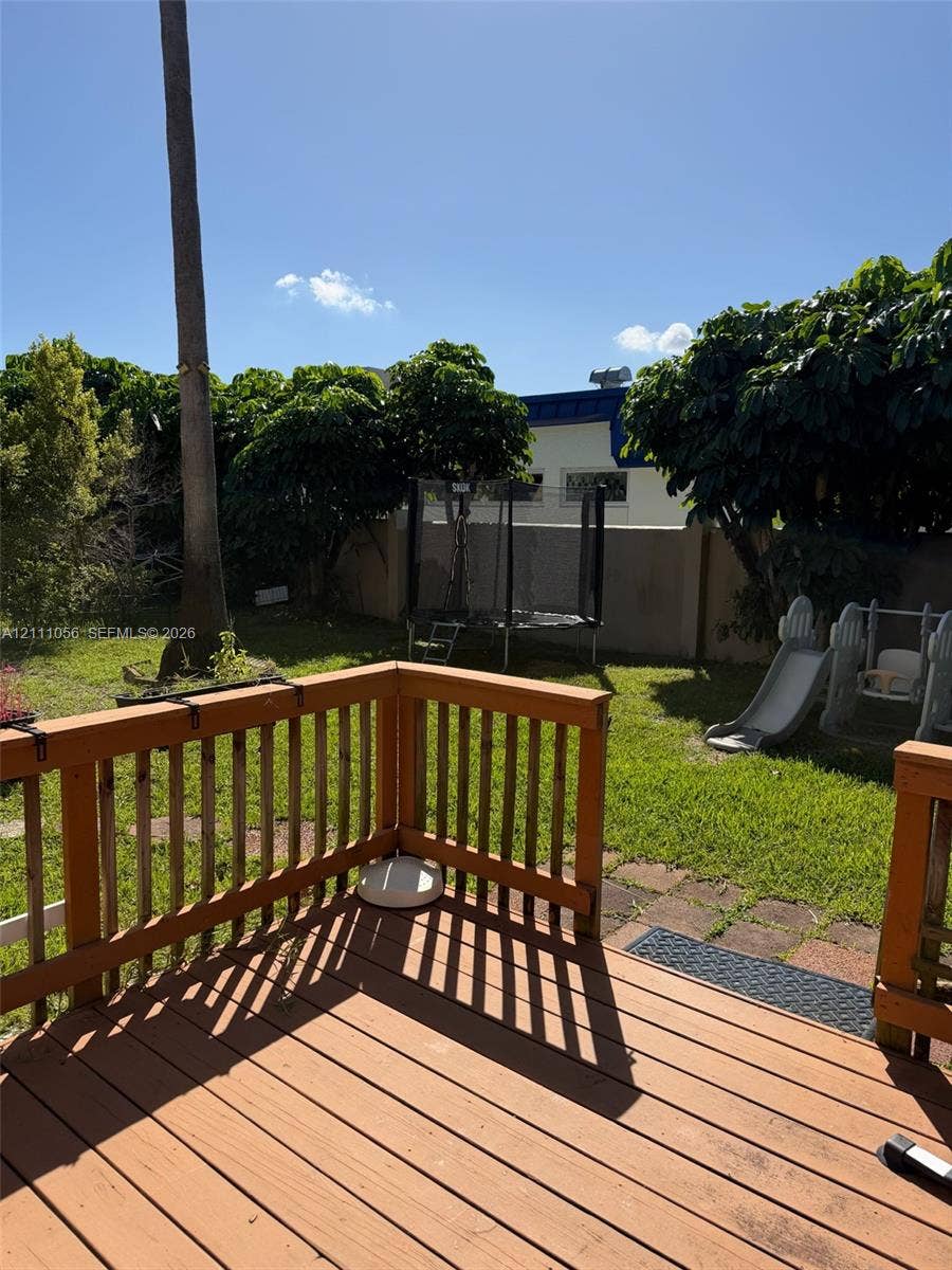 5020 Sheridan Street, #2, Hollywood, FL 33021 Raised wooden deck with railing overlooking a lawn area enclosed by a masonry perimeter wall and mature landscaping