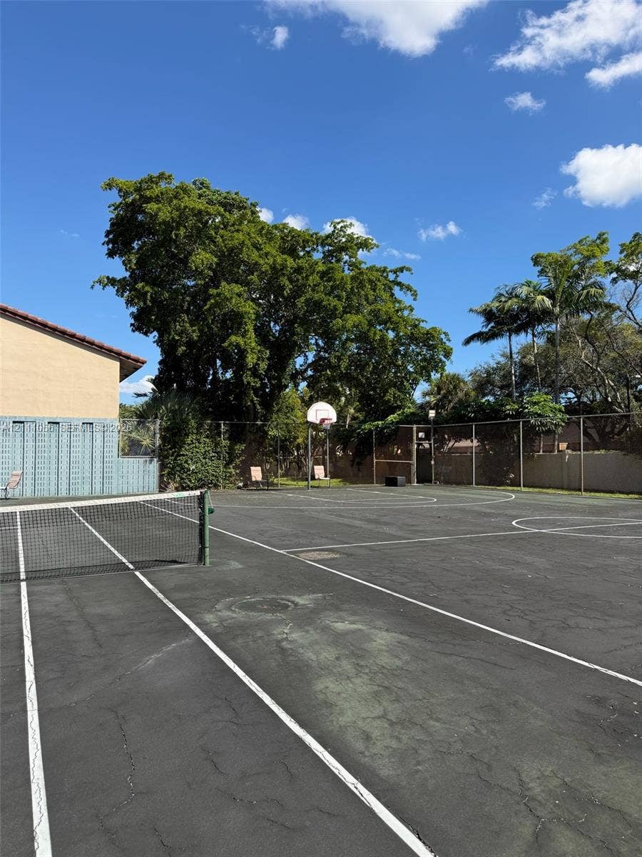 5020 Sheridan Street, #2, Hollywood, FL 33021 Multi-purpose recreation court featuring a basketball hoop, tennis net, perimeter fencing, and mature landscaping