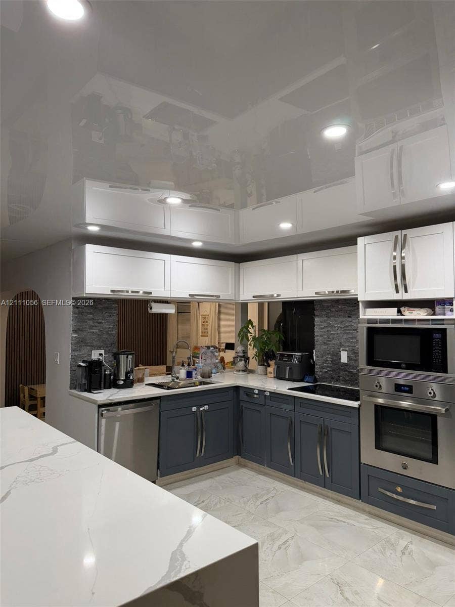 5020 Sheridan Street, #2, Hollywood, FL 33021 Kitchen featuring two-tone cabinetry, high-gloss ceiling finish, stone-surfaced countertops, stone-tile backsplash, and recessed lighting
