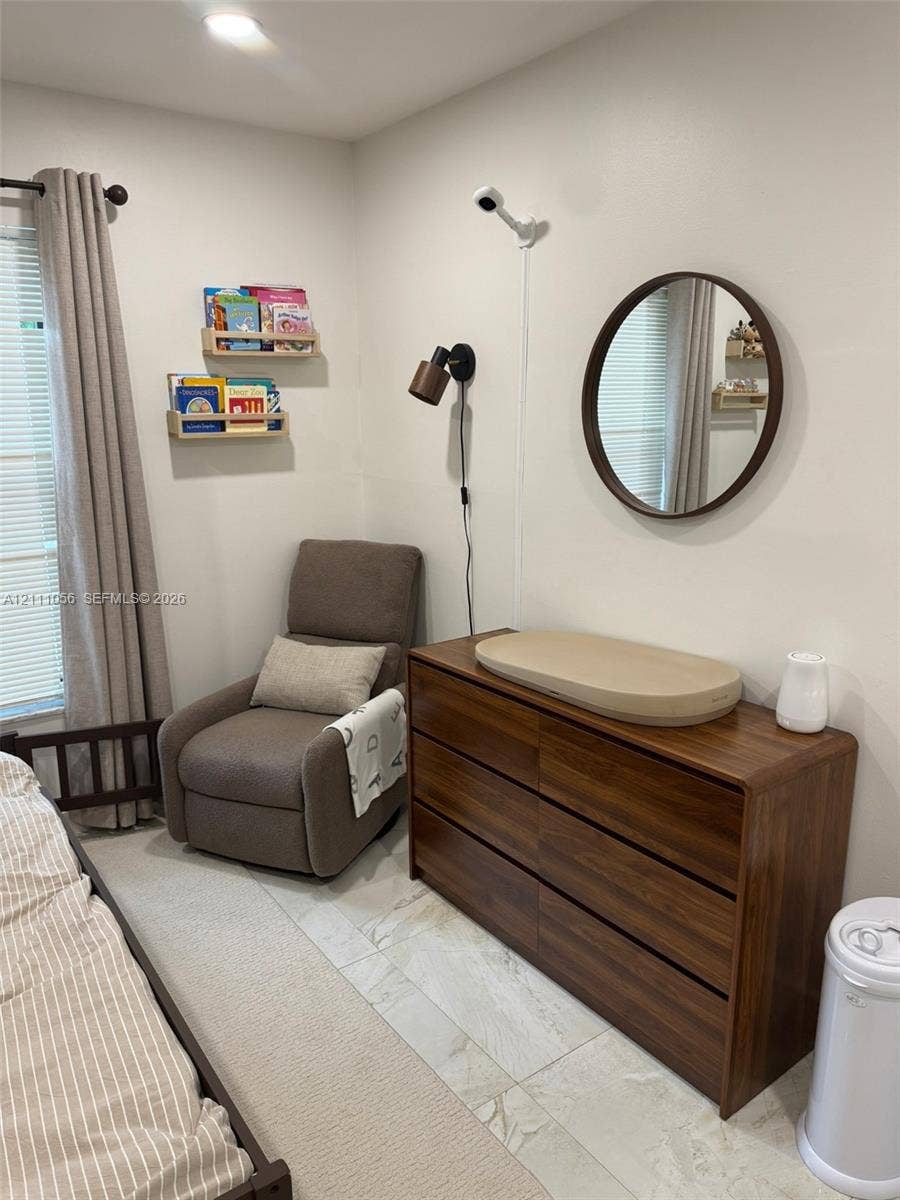 5020 Sheridan Street, #2, Hollywood, FL 33021 Wall-mounted light fixture, circular wall mirror with dark finish, and neutral stone-finish flooring