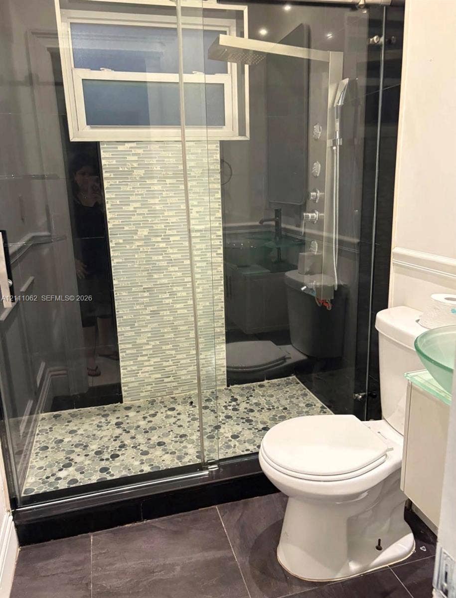 17631 32nd Court, Miami Gardens, FL 33056 Walk-in shower featuring a glass enclosure, pebble-stone flooring, multi-head rainfall shower system, and a decorative mosaic tile accent wall