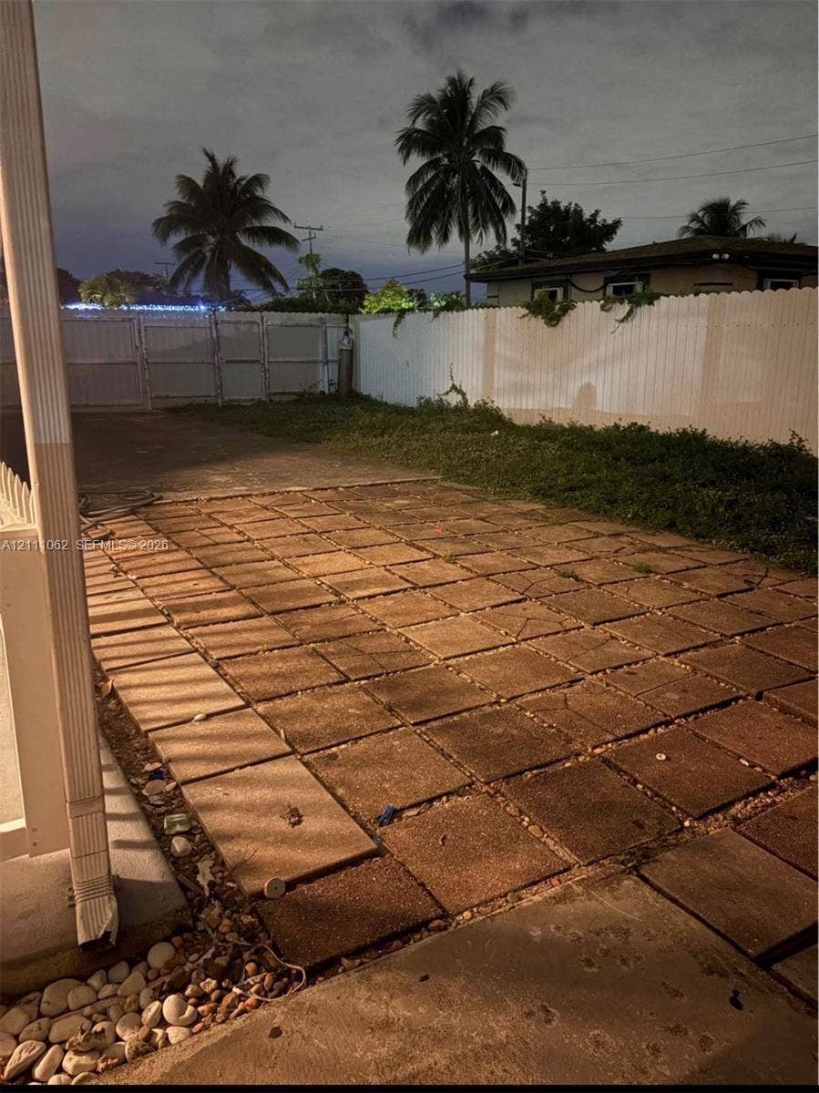 17631 32nd Court, Miami Gardens, FL 33056 Rear patio featuring concrete pavers, enclosed by a white privacy fence with double-gate access