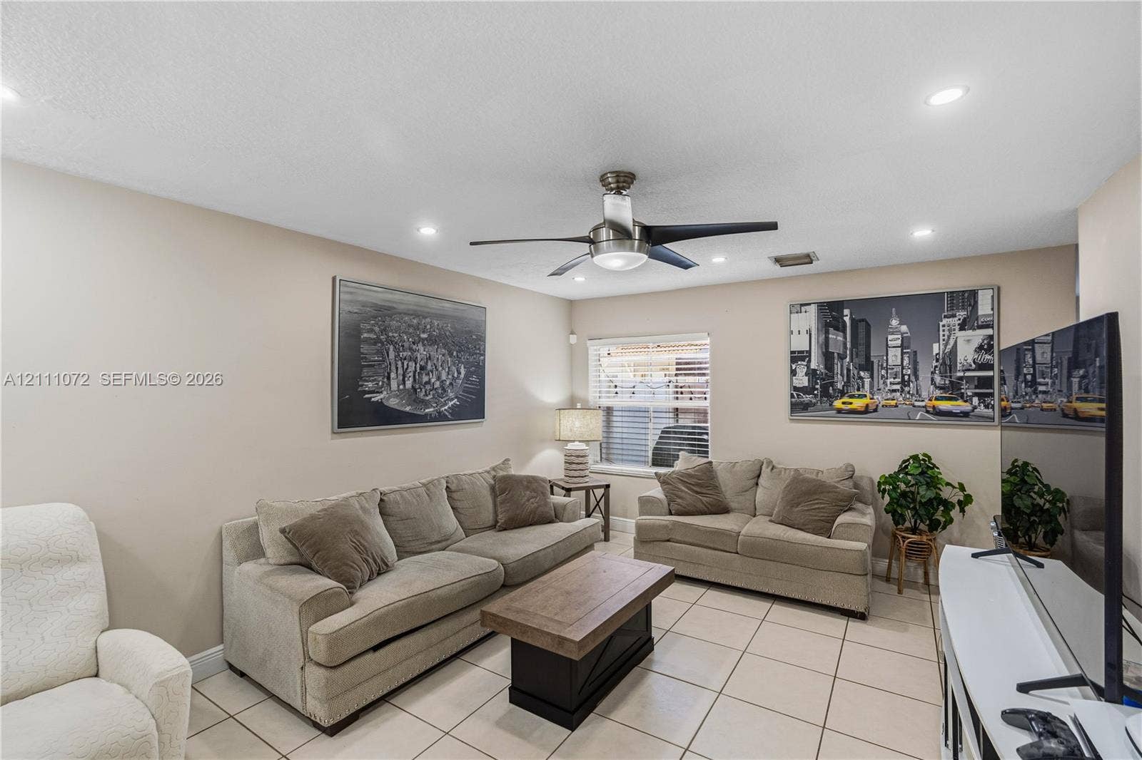Neutral-toned interior space featuring large-format tile flooring, recessed lighting, and a modern metal ceiling fan