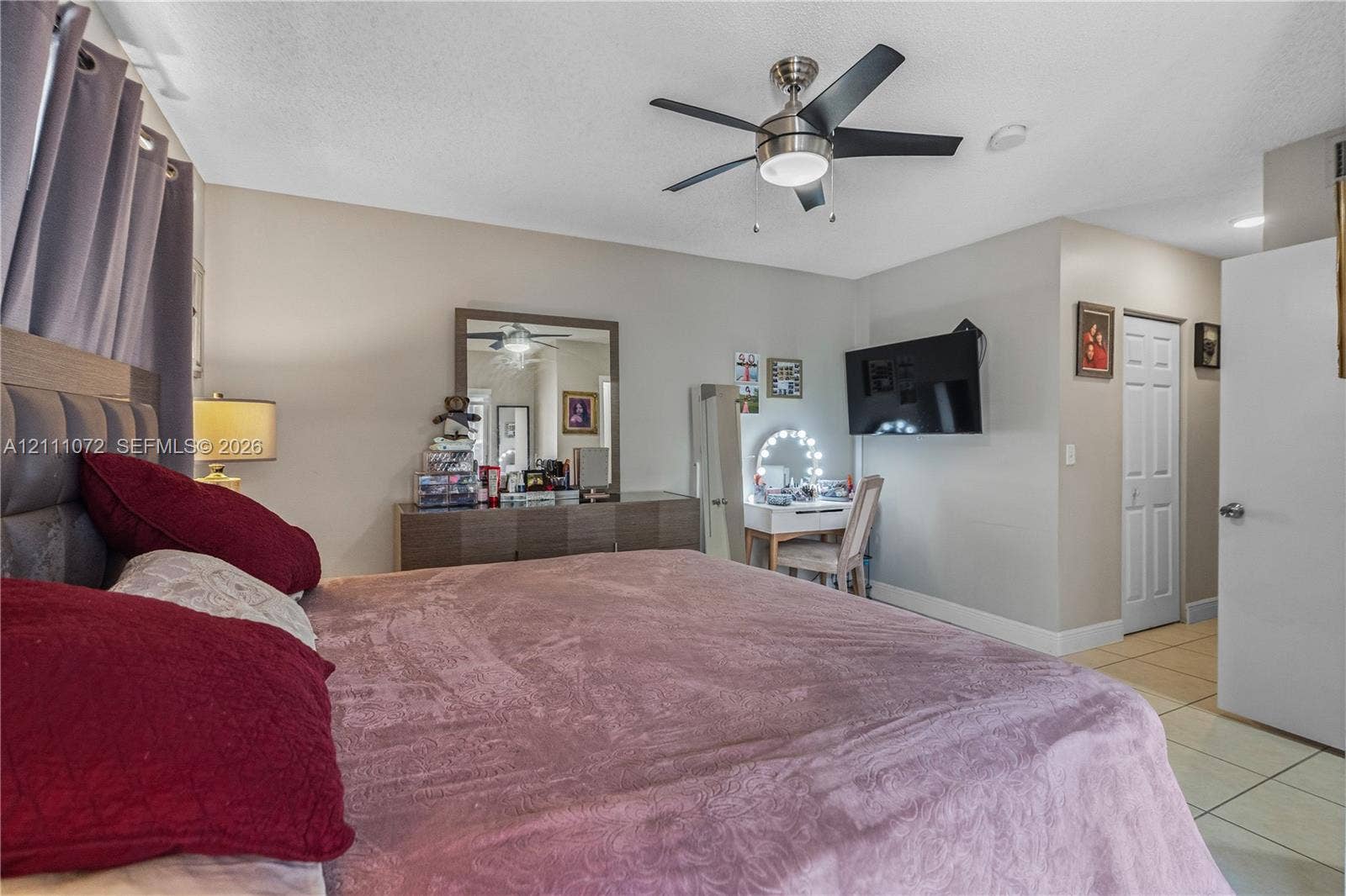 Room featuring ceramic tile flooring, a multi-blade ceiling fan with integrated lighting, and a bi-fold closet door