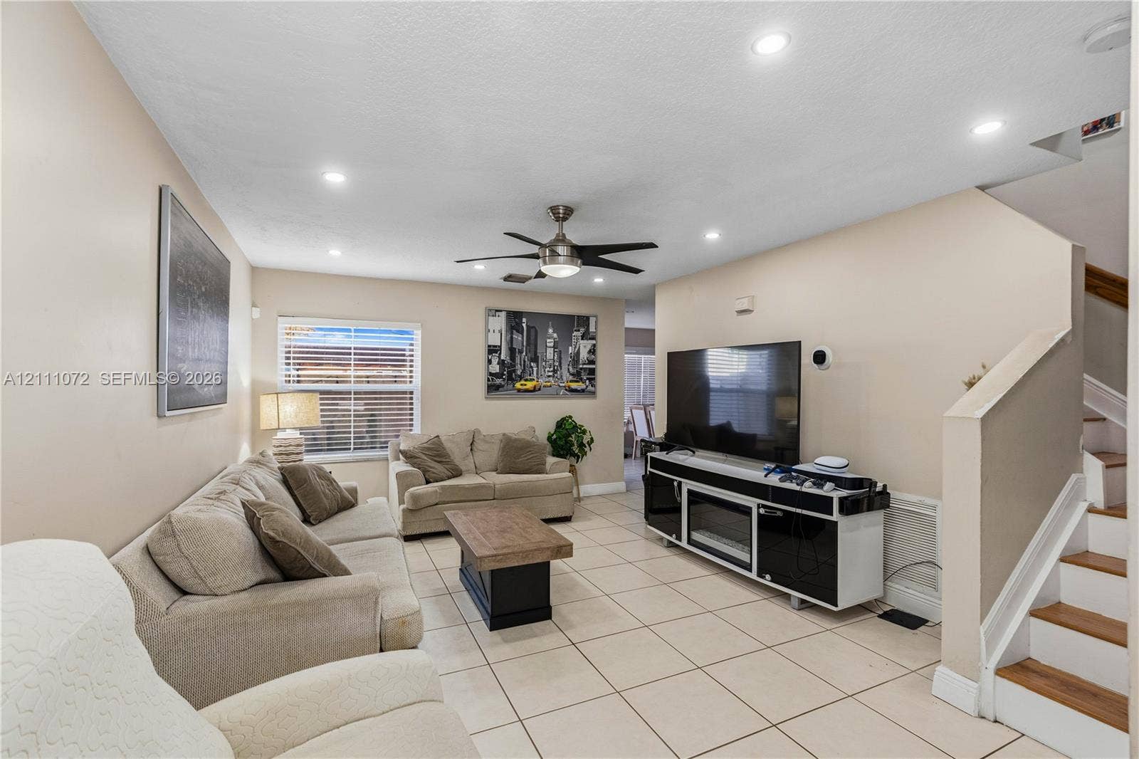 Large-format floor tile, recessed ceiling lighting, ceiling fan, and wooden stair treads
