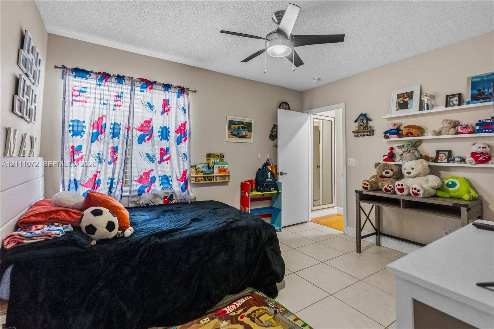 Neutral-toned room featuring tile flooring, a multi-speed ceiling fan with an integrated light fixture, and three wall-mounted floating shelves