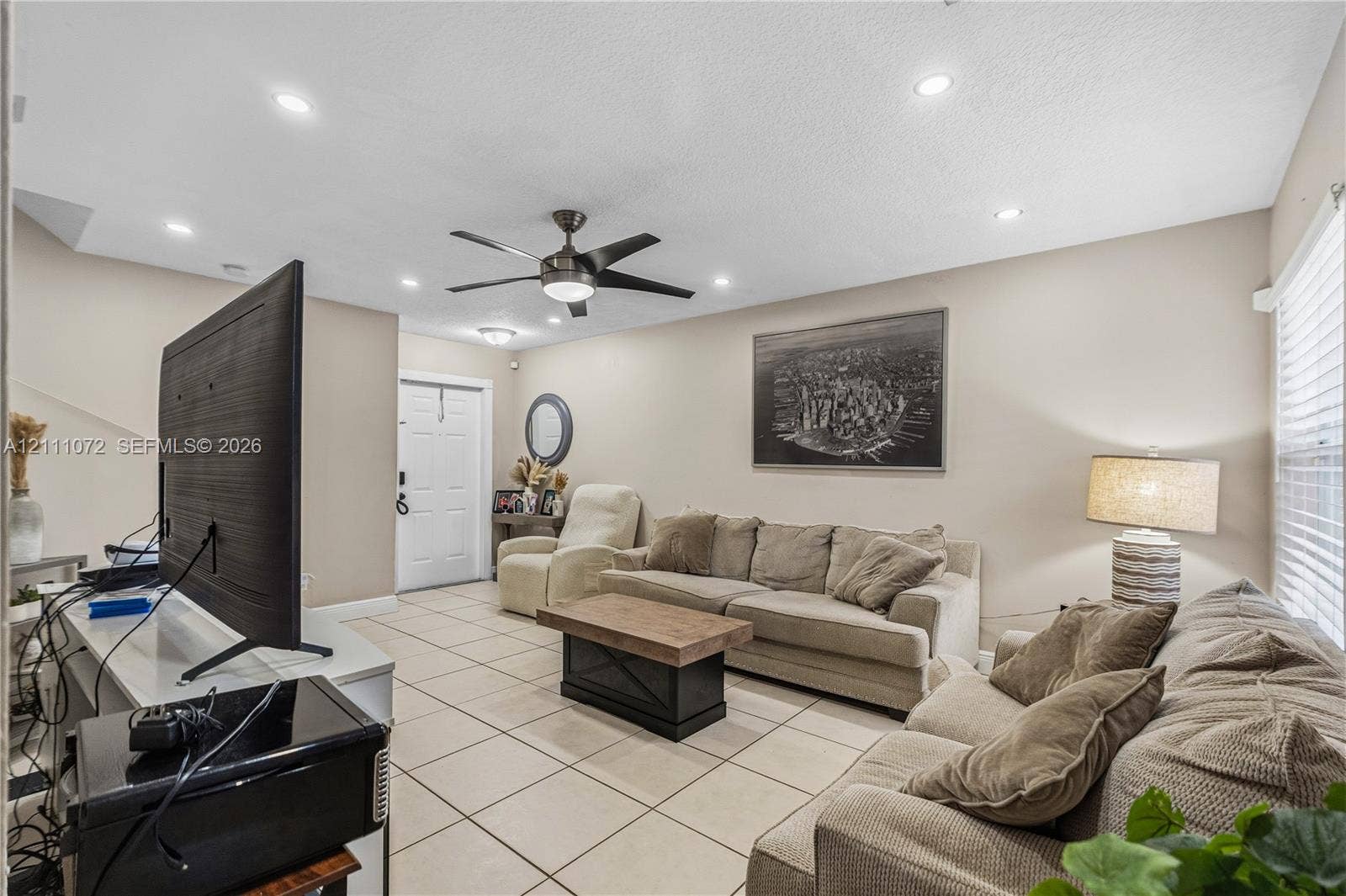 Living area featuring neutral wall tones, large-format tile flooring, recessed ceiling lighting, and a multi-blade ceiling fan