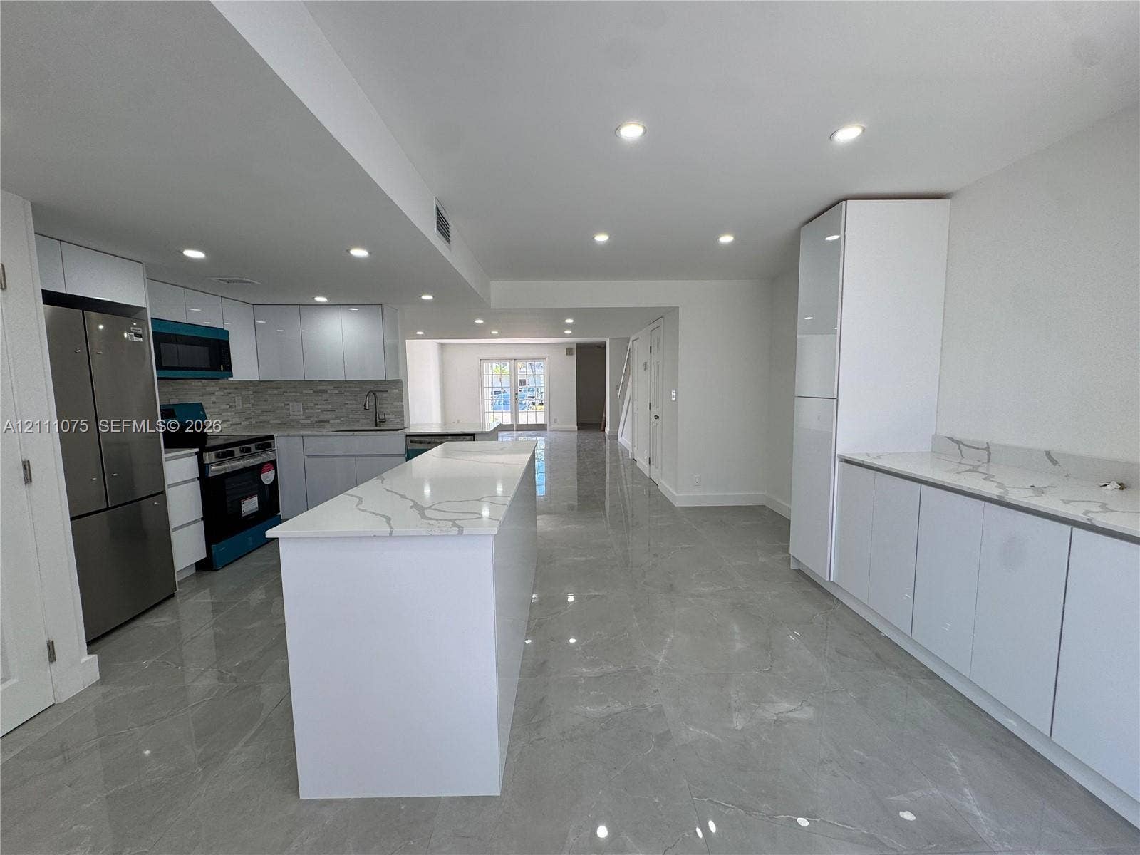 2318 NE 7th Street, #34, Hallandale Beach, Hallandale Beach, FL 33009 Kitchen featuring white slab-front cabinetry, quartz countertops with gray veining, large-format tile flooring, recessed lighting, and stainless steel appliances
