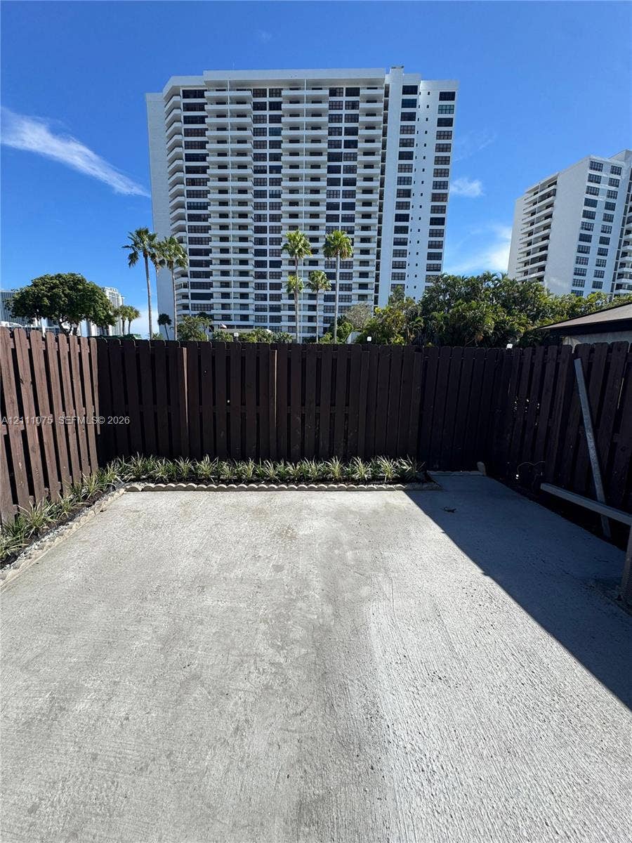 2318 NE 7th Street, #34, Hallandale Beach, Hallandale Beach, FL 33009 Private concrete patio enclosed by vertical wood fencing, featuring stone-bordered landscape beds