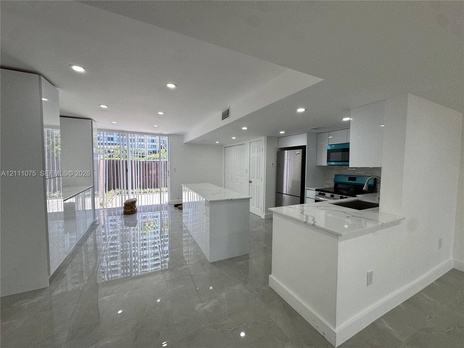 2318 NE 7th Street, #34, Hallandale Beach, Hallandale Beach, FL 33009 Kitchen featuring white gloss cabinetry, stone-finish countertops, central island, stainless steel appliances, and large-format floor tile