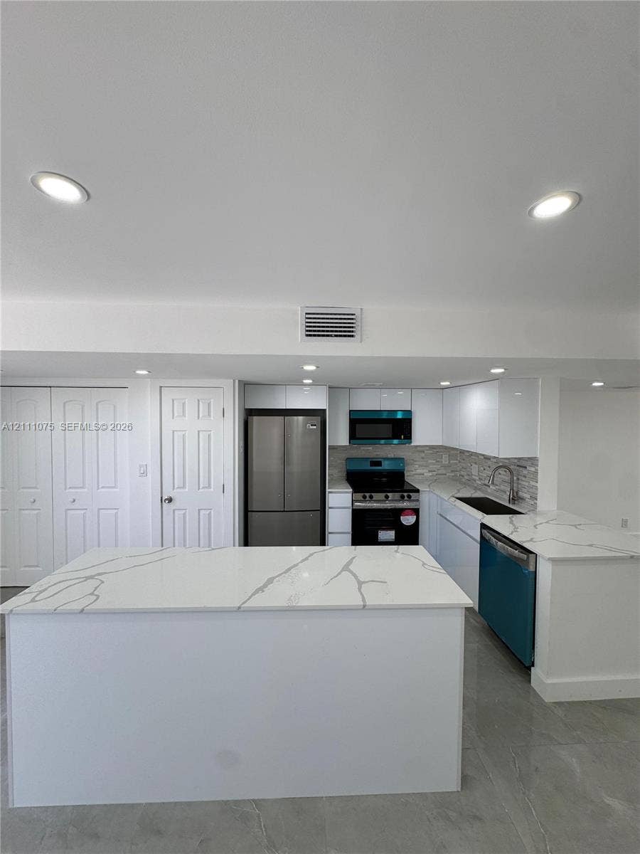 2318 NE 7th Street, #34, Hallandale Beach, Hallandale Beach, FL 33009 Kitchen featuring white cabinetry, stone-finish countertops with veining, a central island, recessed lighting, and stainless steel appliances
