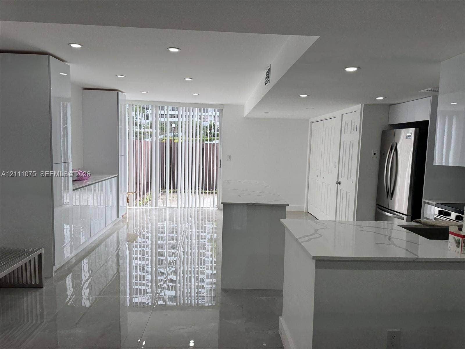 2318 NE 7th Street, #34, Hallandale Beach, Hallandale Beach, FL 33009 Modern kitchen featuring high-gloss cabinetry, stone-surface countertops, polished tile flooring, recessed ceiling lighting, and a stainless steel refrigerator