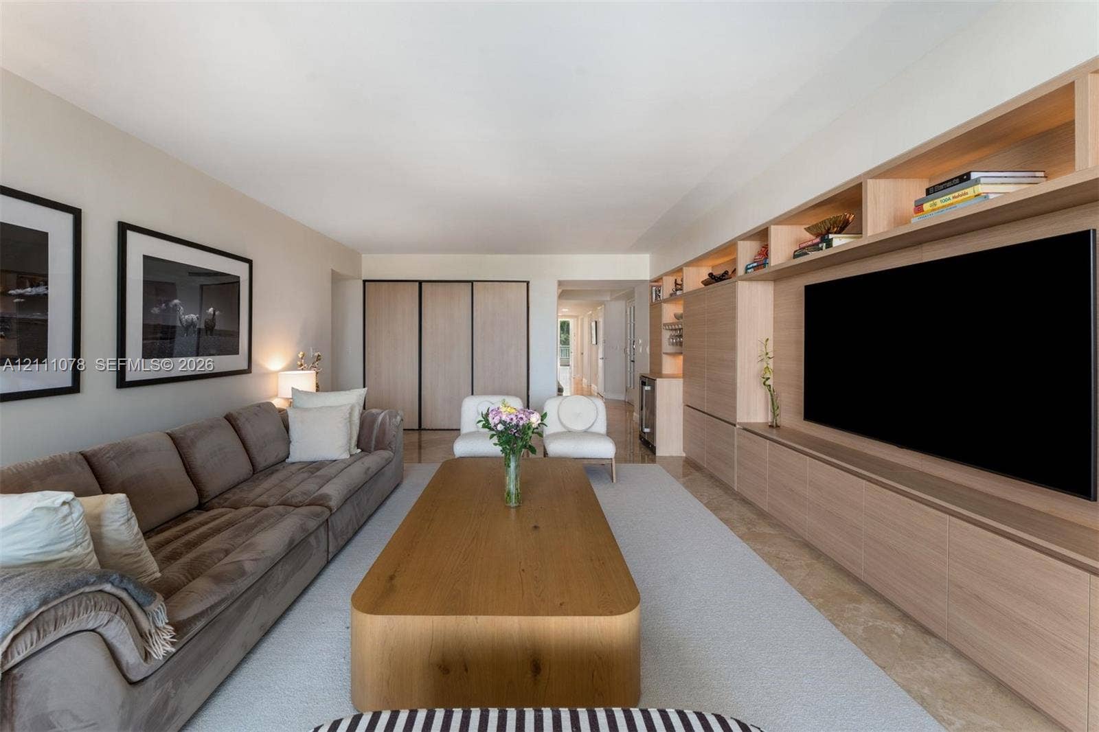 765 Crandon Boulevard, #311, Key Biscayne, FL 33149 Custom wood-finish built-in media cabinetry with integrated shelving, recessed lighting, and stone flooring