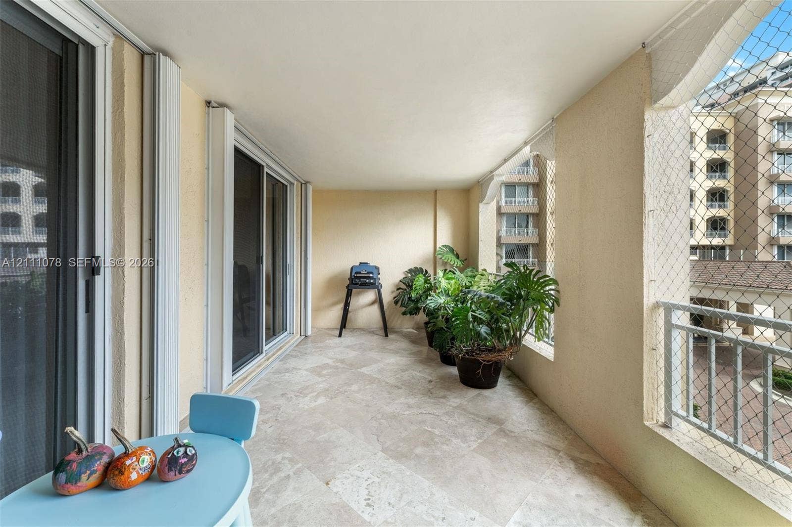 765 Crandon Boulevard, #311, Key Biscayne, FL 33149 Covered balcony featuring stone flooring, sliding glass door access, and protective mesh screening