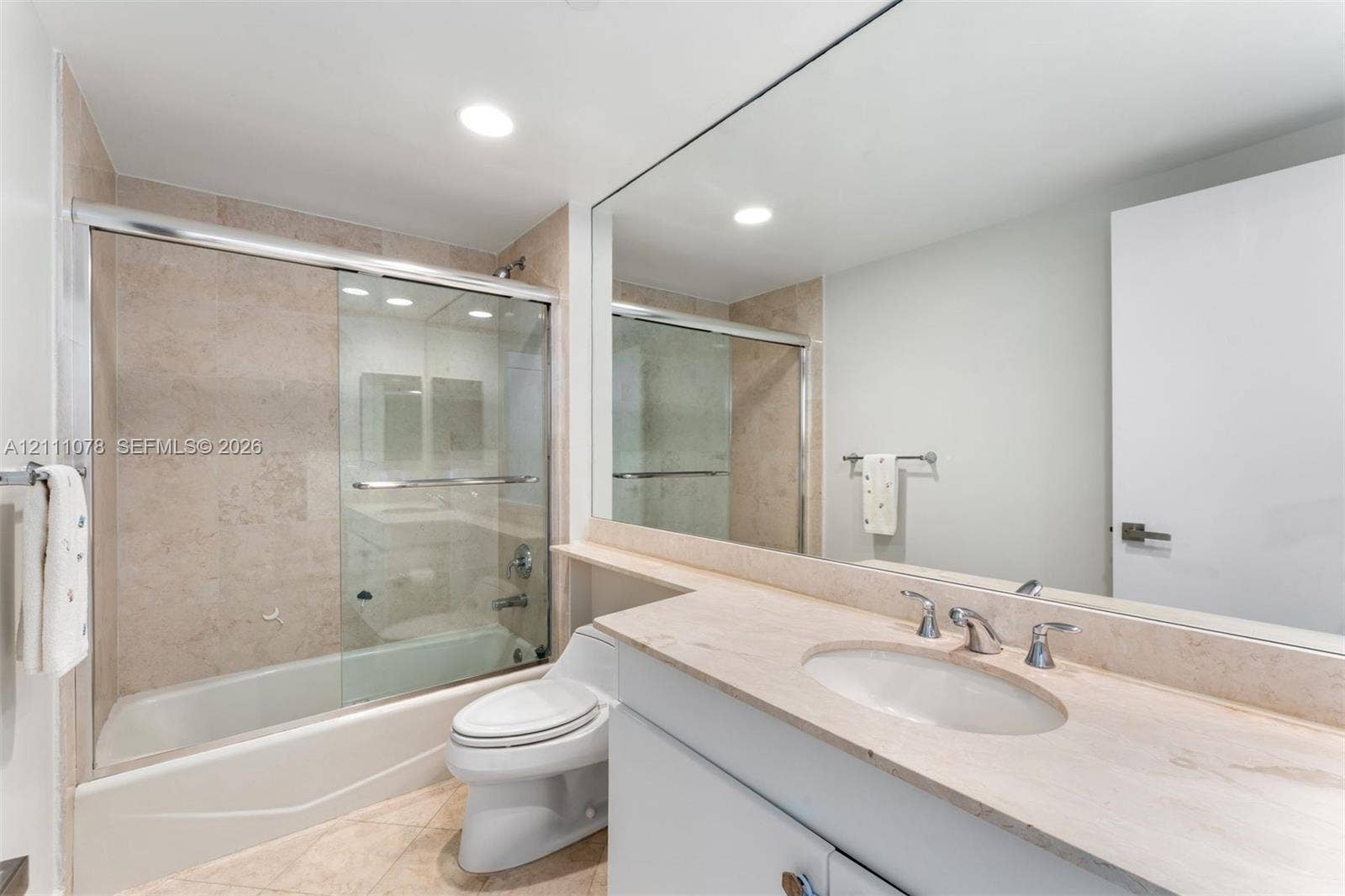 765 Crandon Boulevard, #311, Key Biscayne, FL 33149 Bathroom featuring a vanity with a stone countertop, an integrated sink, a full-width mirror, and a combination tub and shower enclosure with a sliding glass door