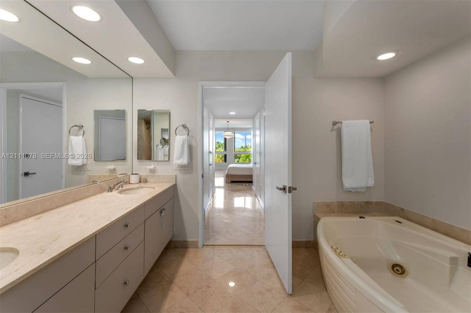 765 Crandon Boulevard, #311, Key Biscayne, FL 33149 Bathroom featuring dual-sink vanity with stone countertop, large wall-mounted mirror, recessed lighting, tile flooring, and jetted tub with stone tile surround