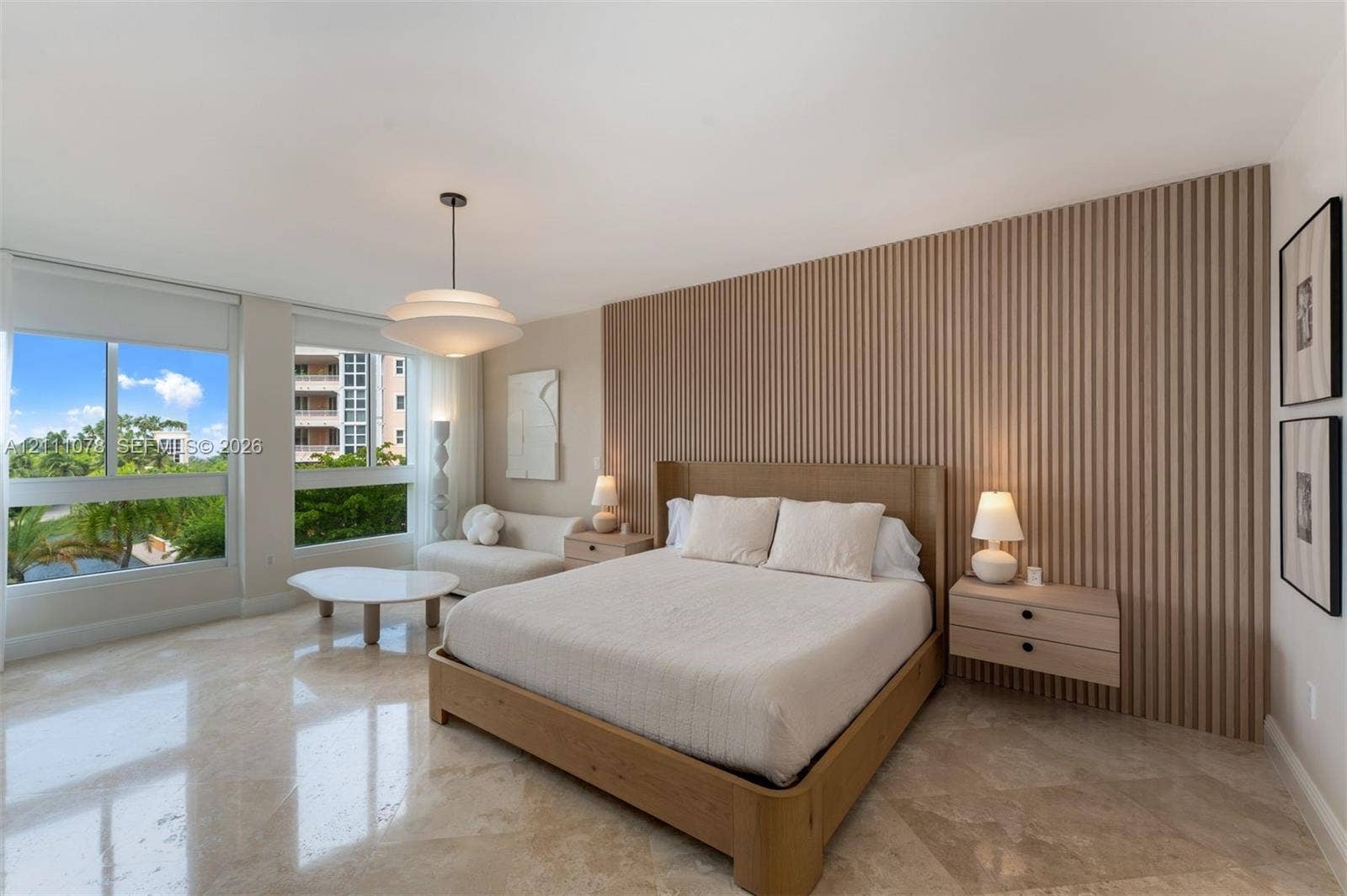 765 Crandon Boulevard, #311, Key Biscayne, FL 33149 Bedroom featuring polished stone flooring, a floor-to-ceiling slatted wood accent wall, floating wood-finish nightstands, and expansive horizontal windows