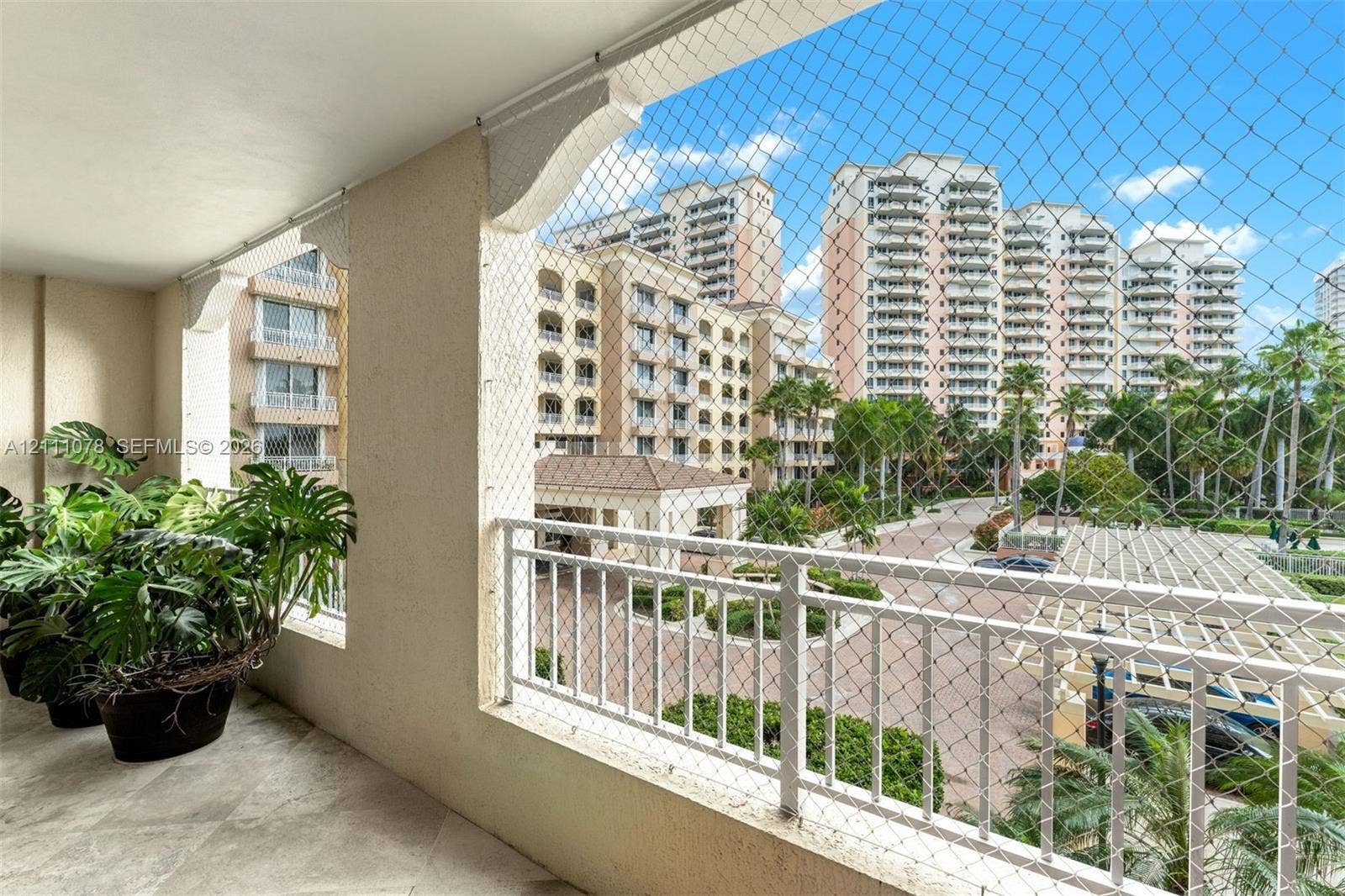 765 Crandon Boulevard, #311, Key Biscayne, FL 33149 Covered balcony featuring stone-finish flooring, decorative corbel accents, and a protective mesh screen enclosure