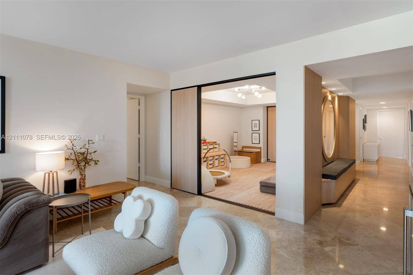 765 Crandon Boulevard, #311, Key Biscayne, FL 33149 Interior space featuring polished stone flooring, custom wood-paneled sliding room divider with black framing, built-in recessed bench seating with circular mirror, and recessed ceiling lighting