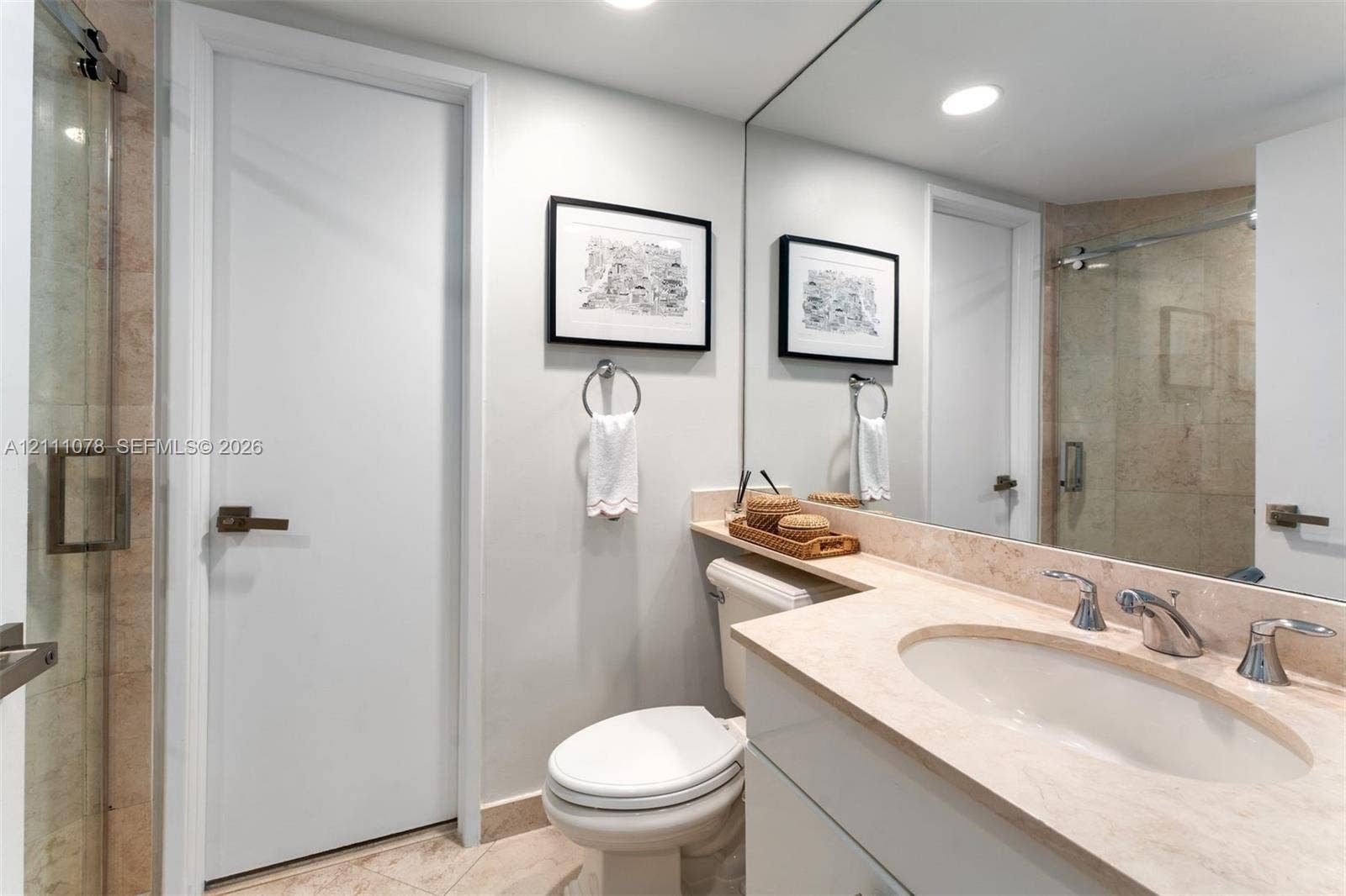 765 Crandon Boulevard, #311, Key Biscayne, FL 33149 Bathroom featuring a stone-surface vanity with an integrated basin, wall-to-wall mirror, glass-enclosed shower, and light-toned floor tiling