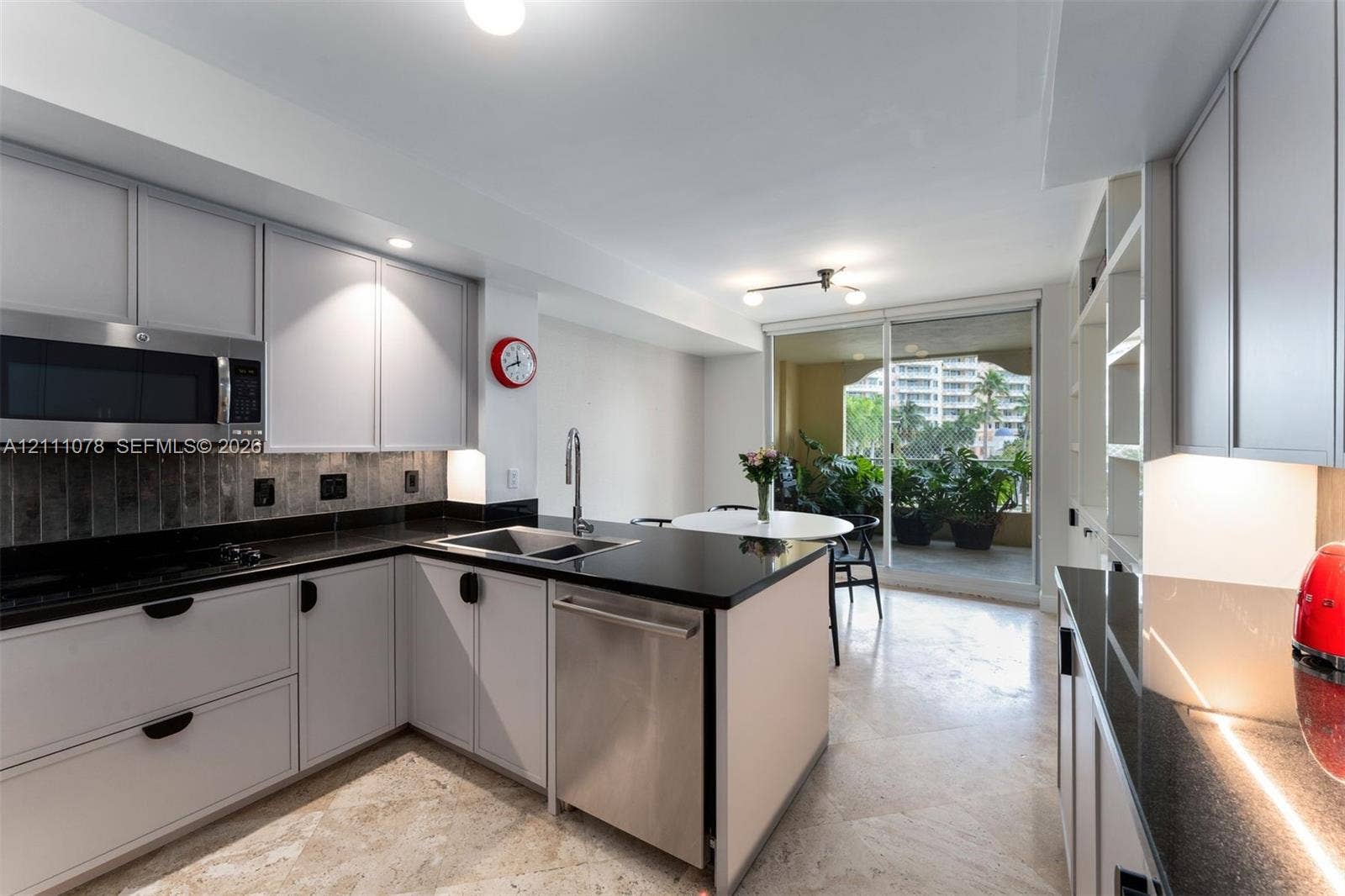 765 Crandon Boulevard, #311, Key Biscayne, FL 33149 Kitchen featuring light-toned cabinetry, dark stone countertops, stainless steel appliances, built-in shelving, and stone tile flooring