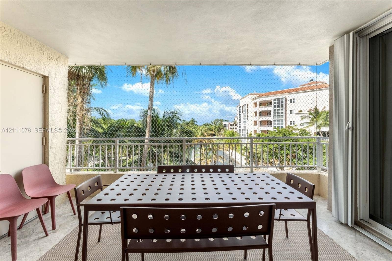 765 Crandon Boulevard, #311, Key Biscayne, FL 33149 Covered balcony featuring stone flooring, white metal railing, and protective mesh screening