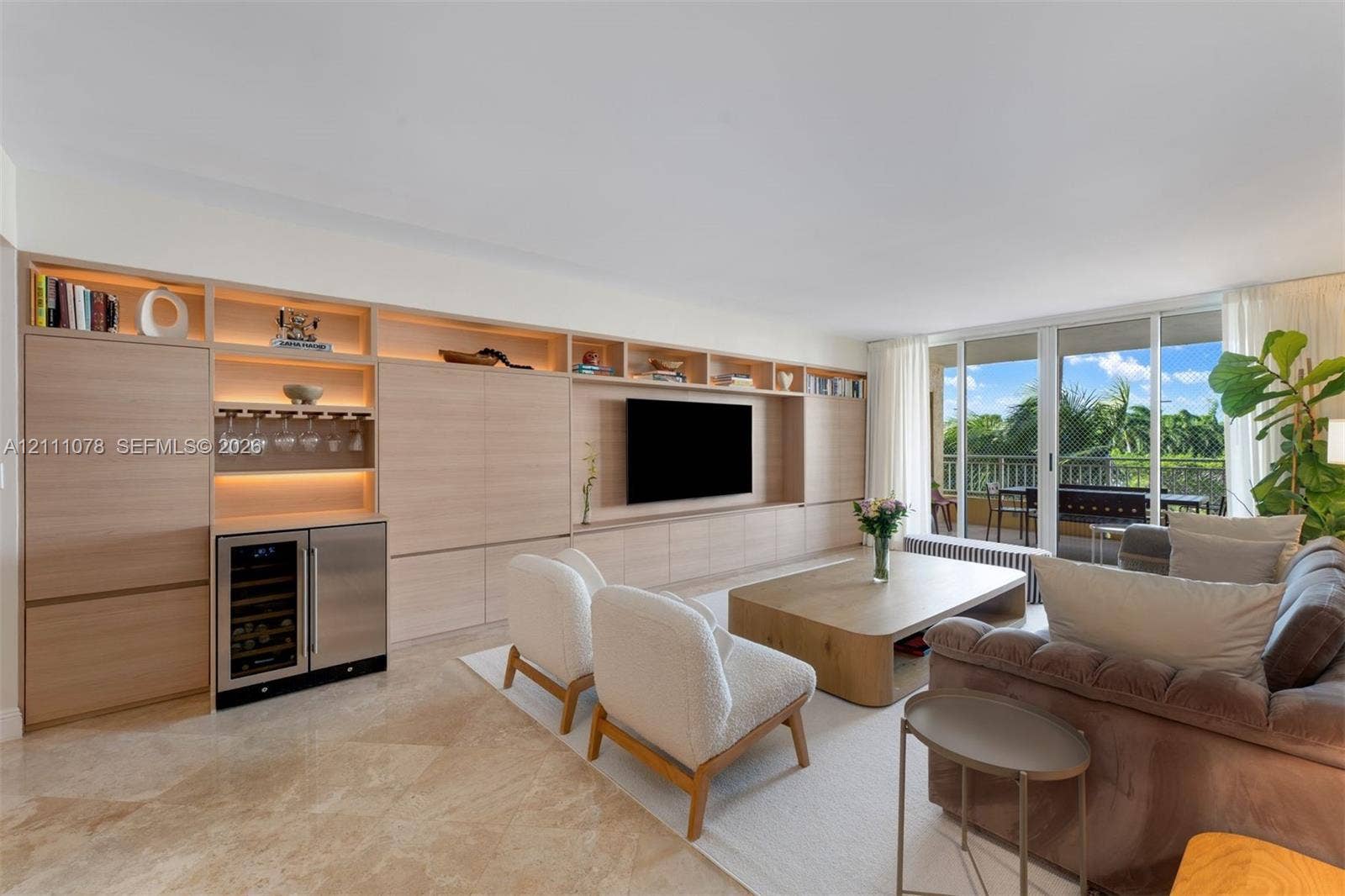 765 Crandon Boulevard, #311, Key Biscayne, FL 33149 Custom wall-to-wall wood cabinetry with integrated shelving, built-in beverage refrigerator, polished stone flooring, and sliding glass doors opening to a covered balcony