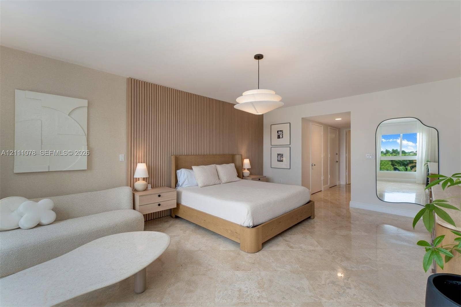 765 Crandon Boulevard, #311, Key Biscayne, FL 33149 Interior space featuring polished stone flooring, custom vertical wood-slat accent wall, and multi-tiered modern pendant lighting