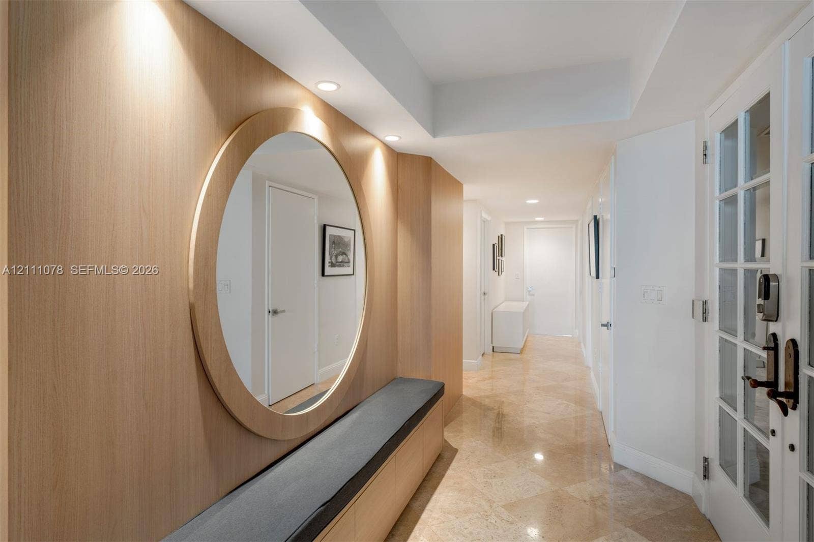 765 Crandon Boulevard, #311, Key Biscayne, FL 33149 Entryway featuring light-toned wood wall paneling, a large circular mirror, integrated bench seating, stone tile flooring, and recessed ceiling lighting