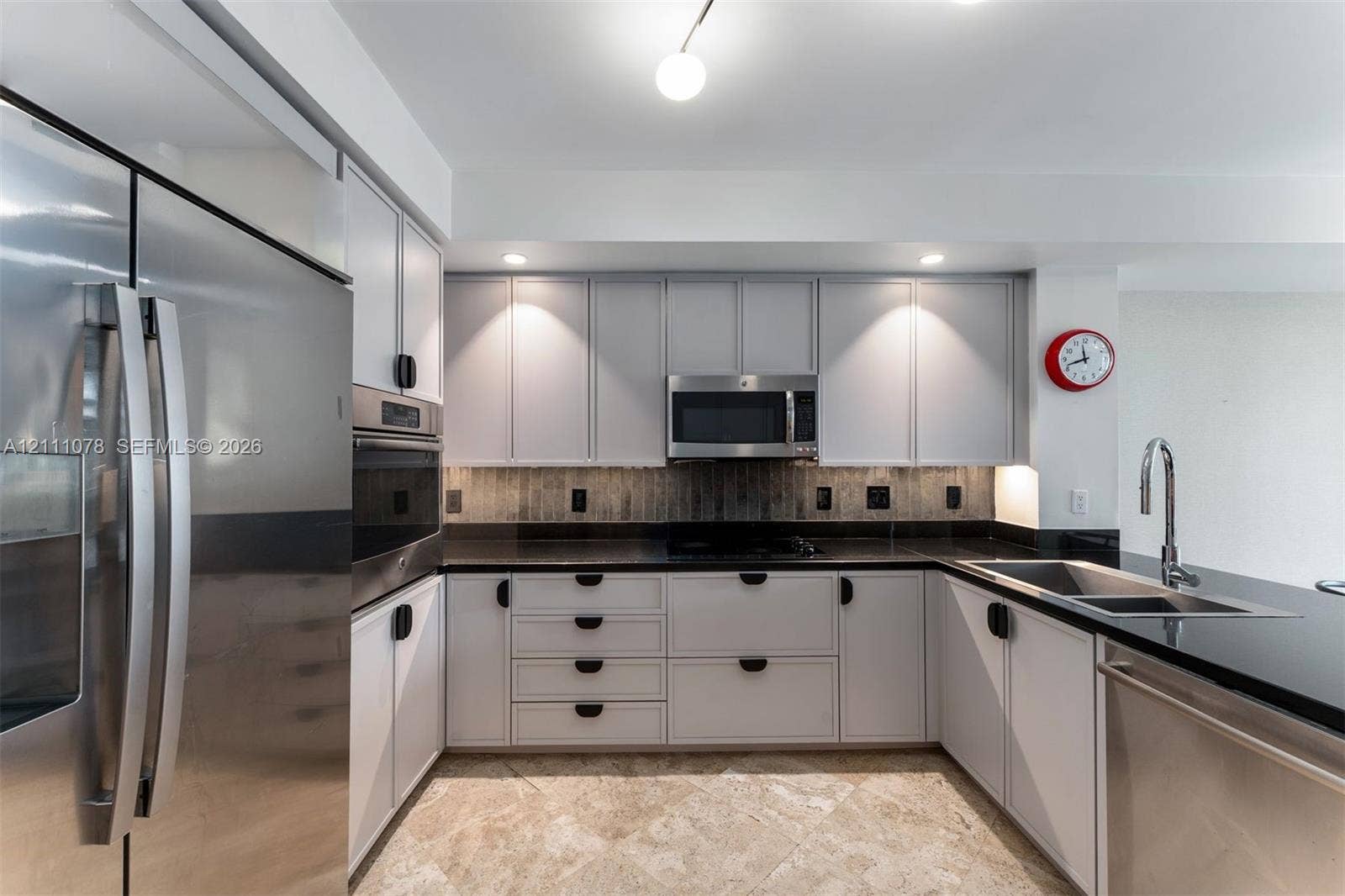 765 Crandon Boulevard, #311, Key Biscayne, FL 33149 Kitchen featuring stainless steel appliances, neutral cabinetry with dark hardware, stone-finish countertops, tile backsplash, and stone-finish flooring