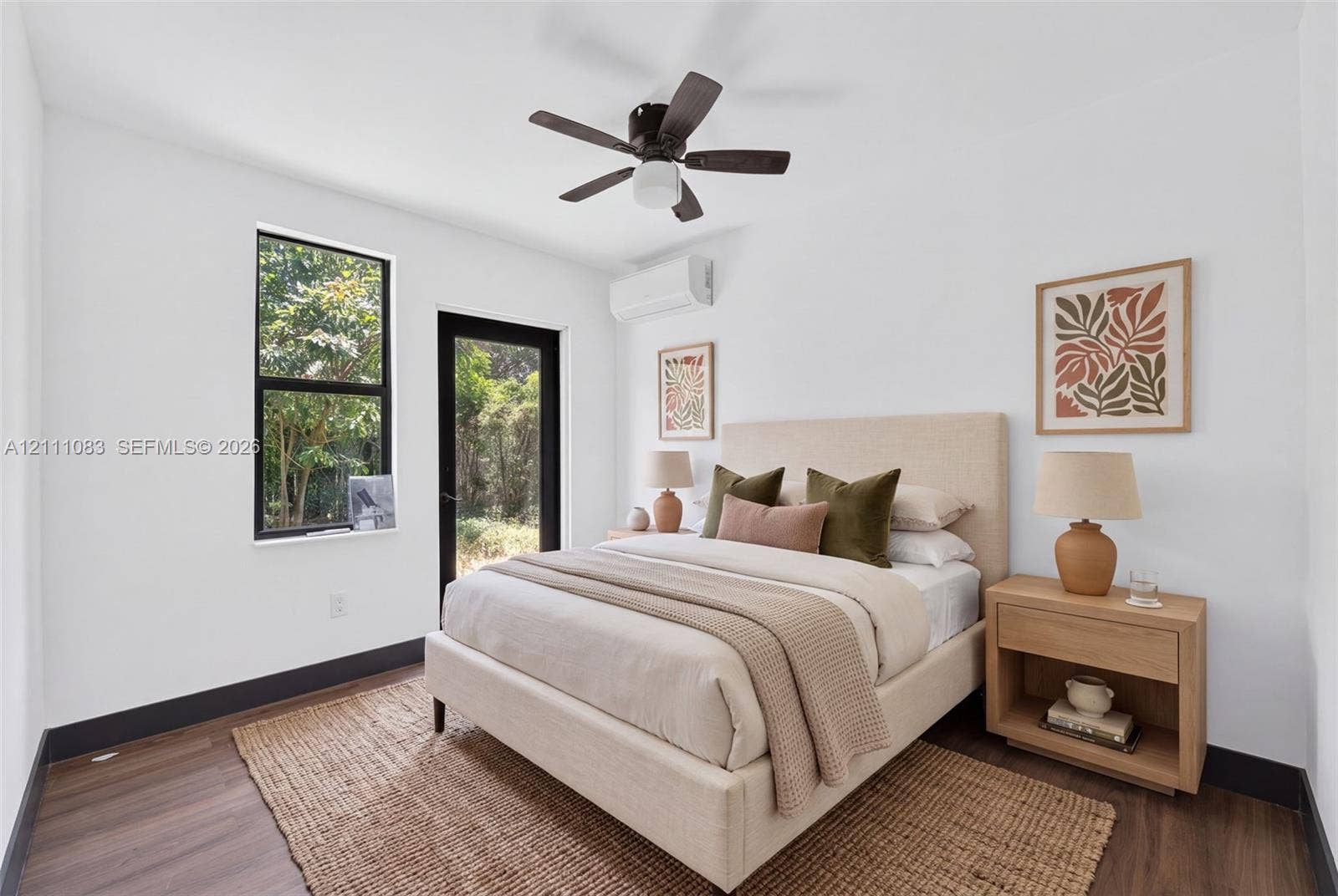 Wood-finish flooring, dark-trimmed window, glass-panel exterior door, wall-mounted ductless climate control unit, and dark-finish ceiling fan