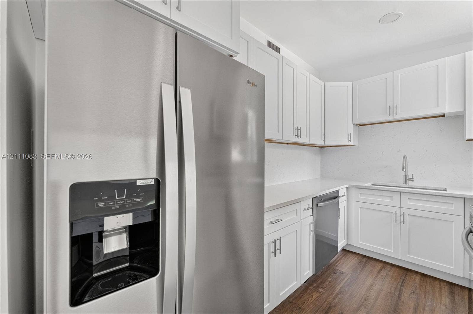 Kitchen featuring stainless steel appliances, shaker-style cabinetry, solid-surface countertops, undermount sink with a gooseneck faucet, and wood-finish flooring