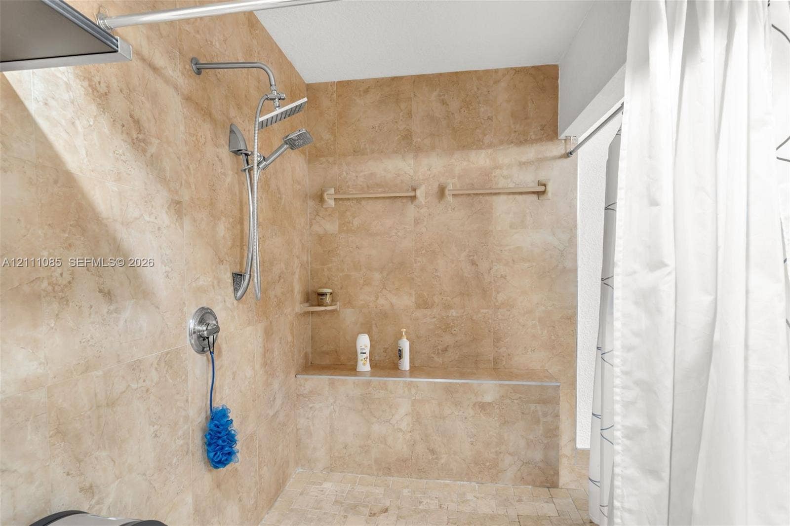 Walk-in shower featuring floor-to-ceiling stone tile, a built-in stone bench, and a dual-head stainless steel shower system