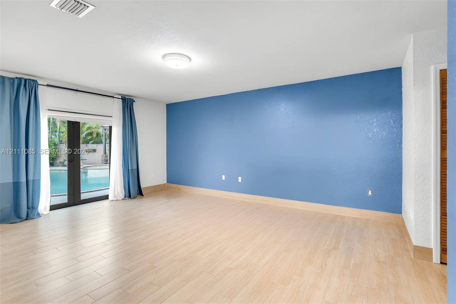 Interior space featuring wood-finish tile flooring, accent wall, and glass-paneled doors