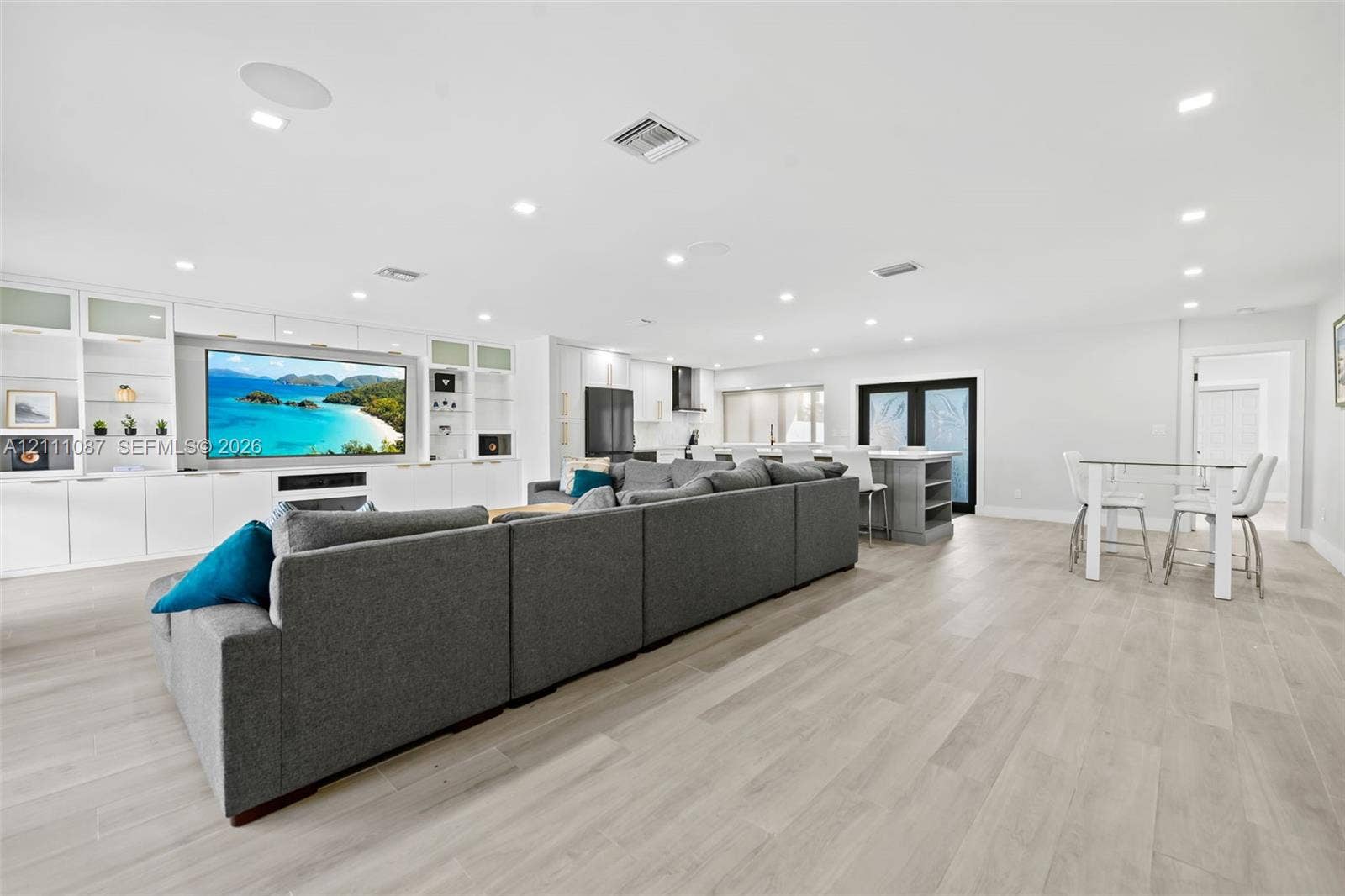 822 Polk Street, Hollywood, FL 33019 Open-concept living space featuring wood-finish flooring, recessed lighting, and custom floor-to-ceiling built-in cabinetry with integrated media center