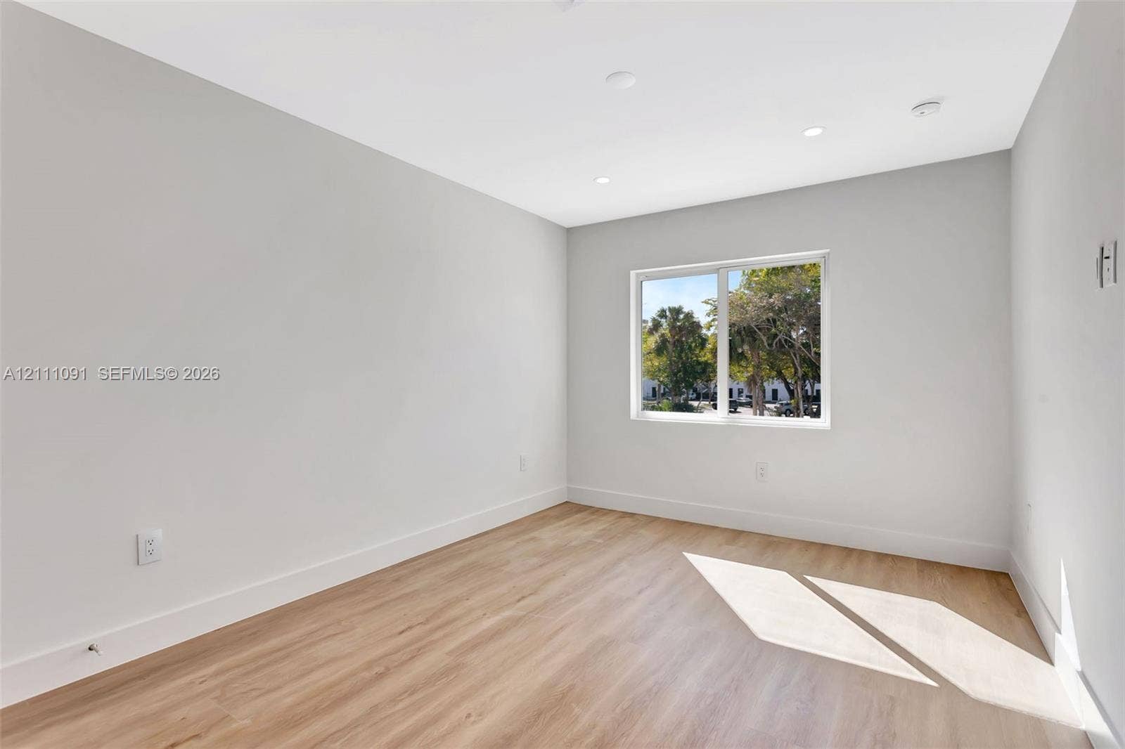 Interior space featuring neutral wall paint, wood-finish flooring, recessed lighting, and a single-pane window