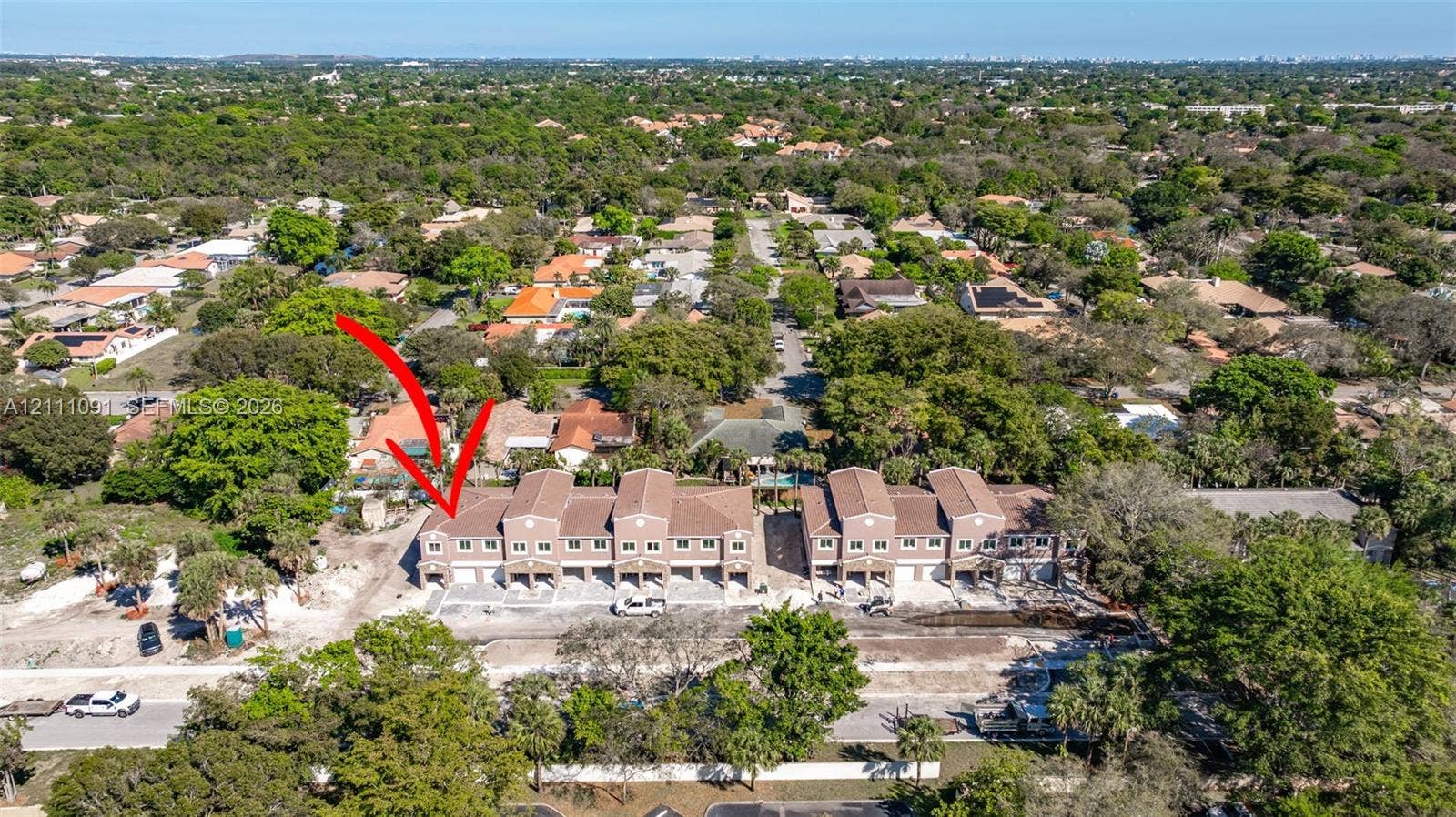 Multi-unit residential complex featuring multi-level construction, clay-tile roofing, integrated garage spaces, and paved driveway access