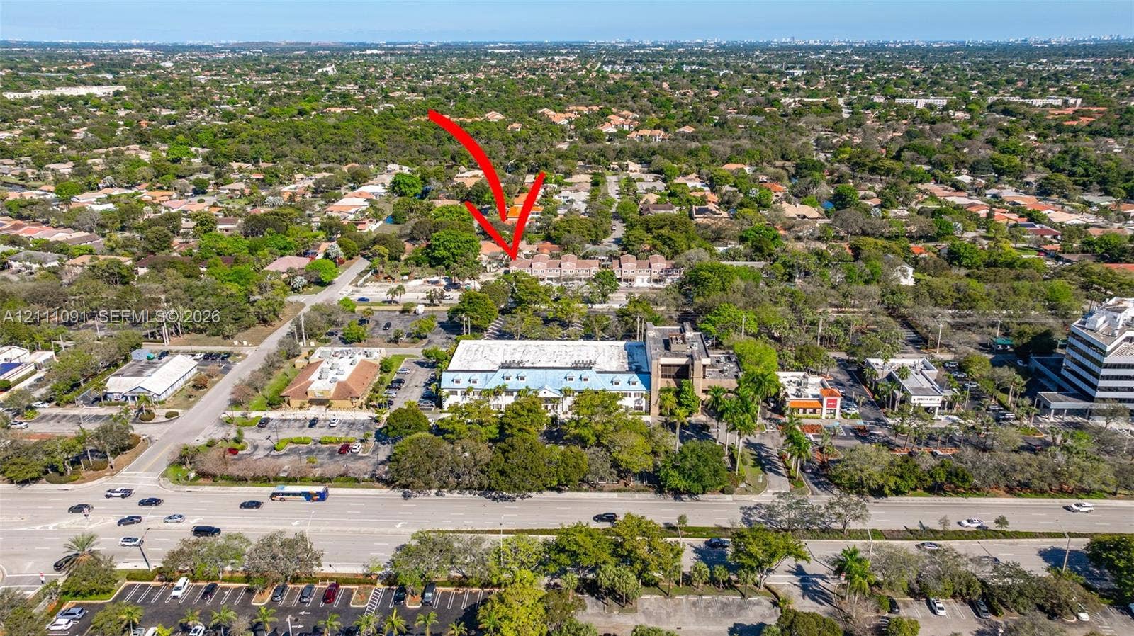 Aerial perspective featuring a multi-unit residential structure with tiled roofing, surrounded by mature tree canopy and established vegetation