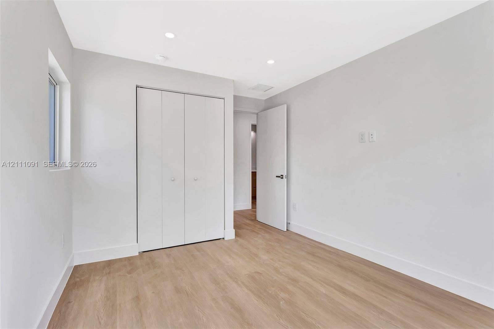 Neutral interior space featuring wood-finish flooring, recessed lighting, and a bi-fold closet