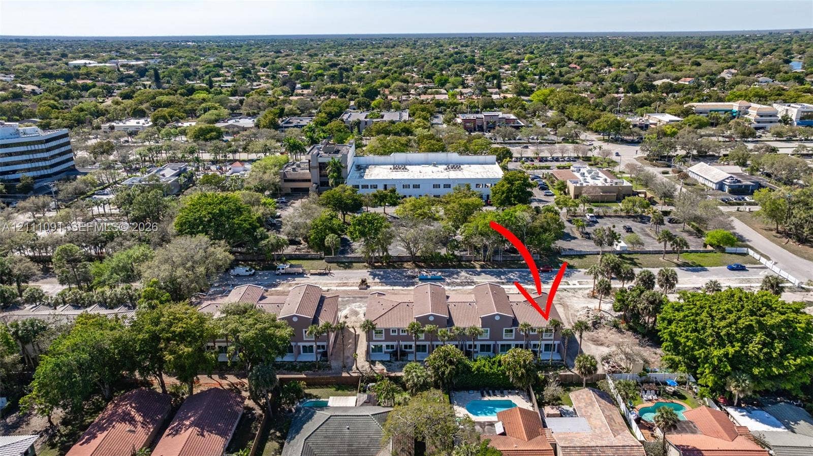 Aerial perspective featuring multi-story residential buildings with shingled rooflines and palm-lined landscaping