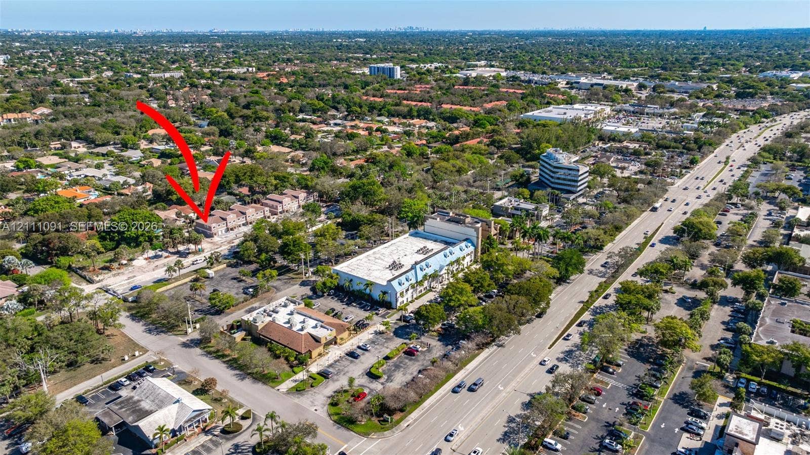 Aerial perspective of the property featuring a multi-story building situated within a dense canopy of mature trees